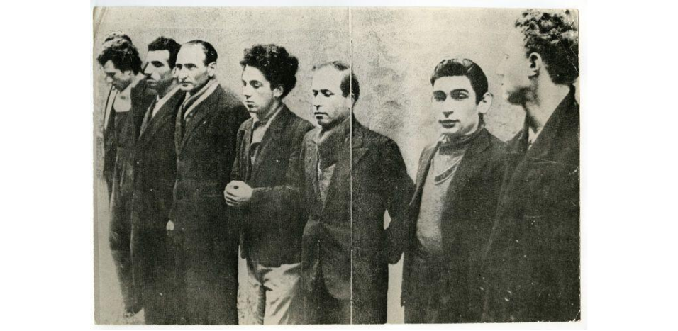 Photographie noir et blanc sur laquelle figurent sept des membres du groupe Manouchian. Missak Manouchian est le 2e à partir de la gauche
